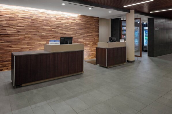A reception desk with a wooden wall backdrop, a digital screen, and a counter.