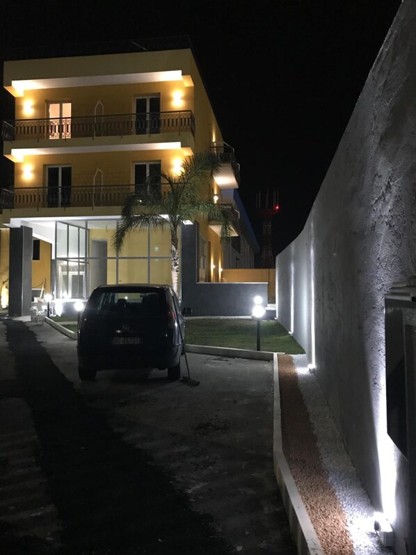 A two-story building with a balcony, a parked car, and a well-lit entrance. - Borgo Palombaio (Catania)