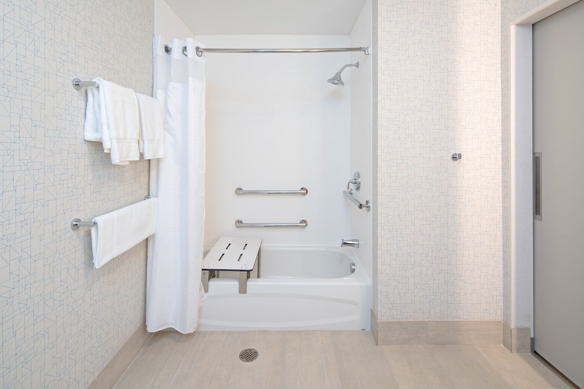 A modern bathroom with a shower, a grab bar, and a small step for accessibility.