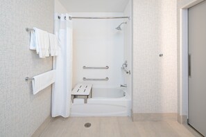 Een moderne badkamer met een douche, een handgreep en een klein opstapje voor toegankelijkheid.