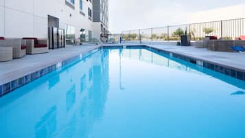 Una piscina al aire libre, sillones reclinables de piscina