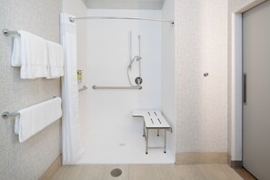 Een moderne badkamer met een inloopdouche, handgrepen en een zitje.