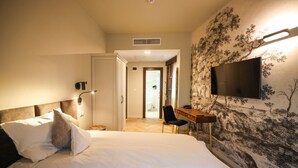 A hotel room with a bed, a desk, a chair, a TV, and a door leading to a bathroom. - Pensiunea Nora (Timisoara)