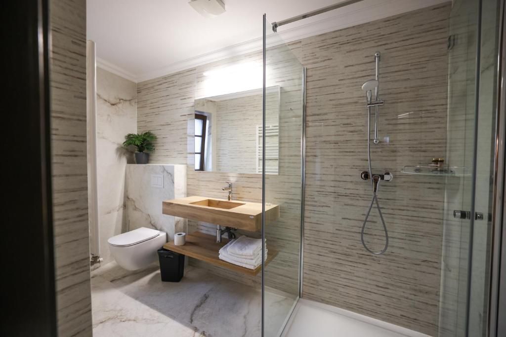 A modern bathroom with a glass-enclosed shower, a wooden vanity, and a marble wall.