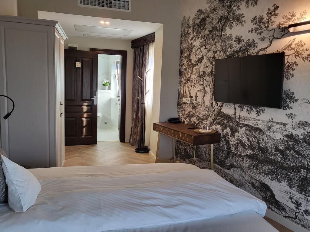 Un dormitorio con cama, escritorio, televisor y puerta que da a un baño.