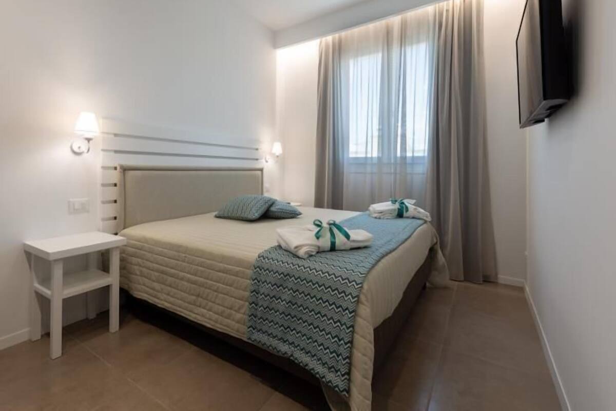 A neatly arranged hotel room with a bed, bedside table, and a TV mounted on the wall.
