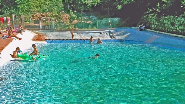 A swimming pool with clear water, a diving board, and people swimming and playing. - Camping le P'Tit Bonheur (Escaro)