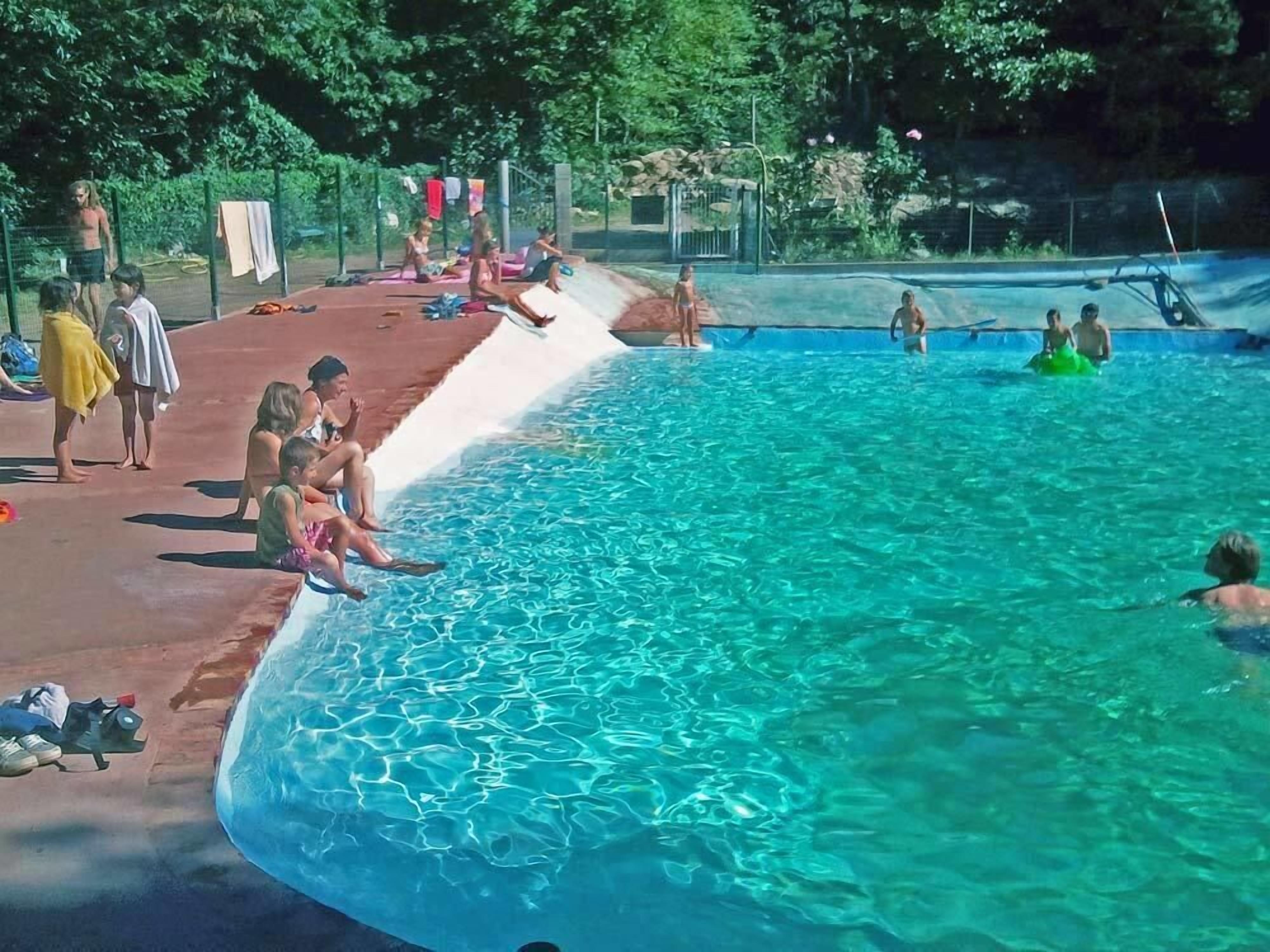 A swimming pool with clear water, surrounded by a covered deck area.