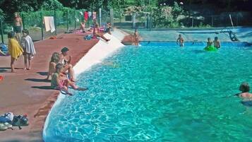 A swimming pool with clear water, surrounded by a covered deck area.