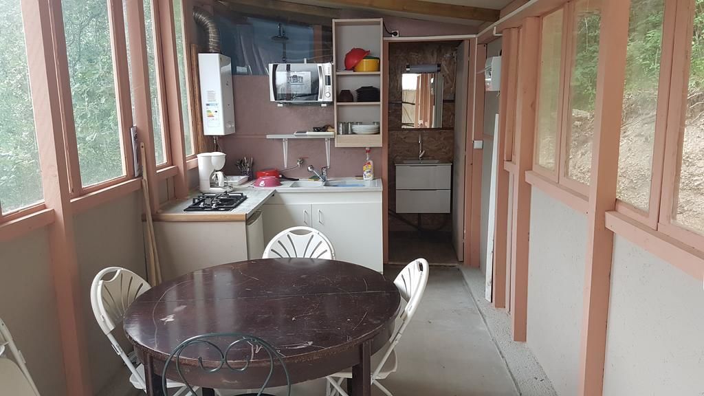 Une cuisine compacte comprenant une table à manger, des chaises, un four à micro-ondes et un évier.