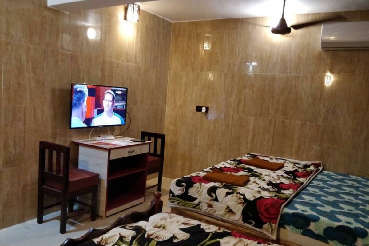 Hotelkamer met een bed, een bureau met stoel, een televisie en een wandairconditioner.
