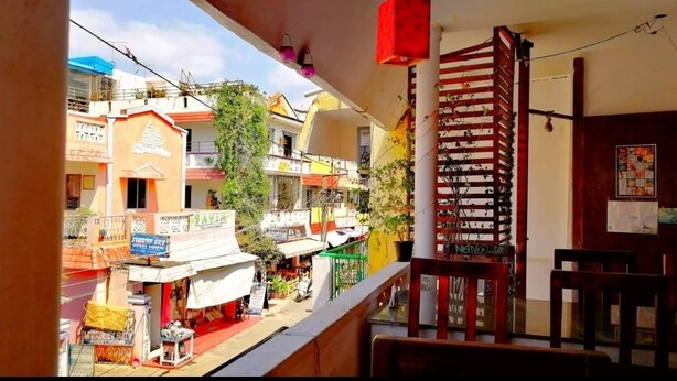 A balcony with a view of a street lined with shops and buildings. - Rajalakshmi Guest House (Tirukalukundram)