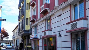 A cobblestone street with outdoor seating, a red carpet, and buildings with balconies and signage for hotels. - Le Safran Palace (Istanbul)