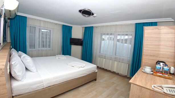 A hotel room with a bed, a desk with a telephone, a television, and a minibar. - Le Safran Palace (Istanbul)