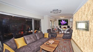 A modern living room with a dark brown sofa, yellow cushions, a wooden coffee table, and a patterned rug. - Le Safran Palace (Istanbul)