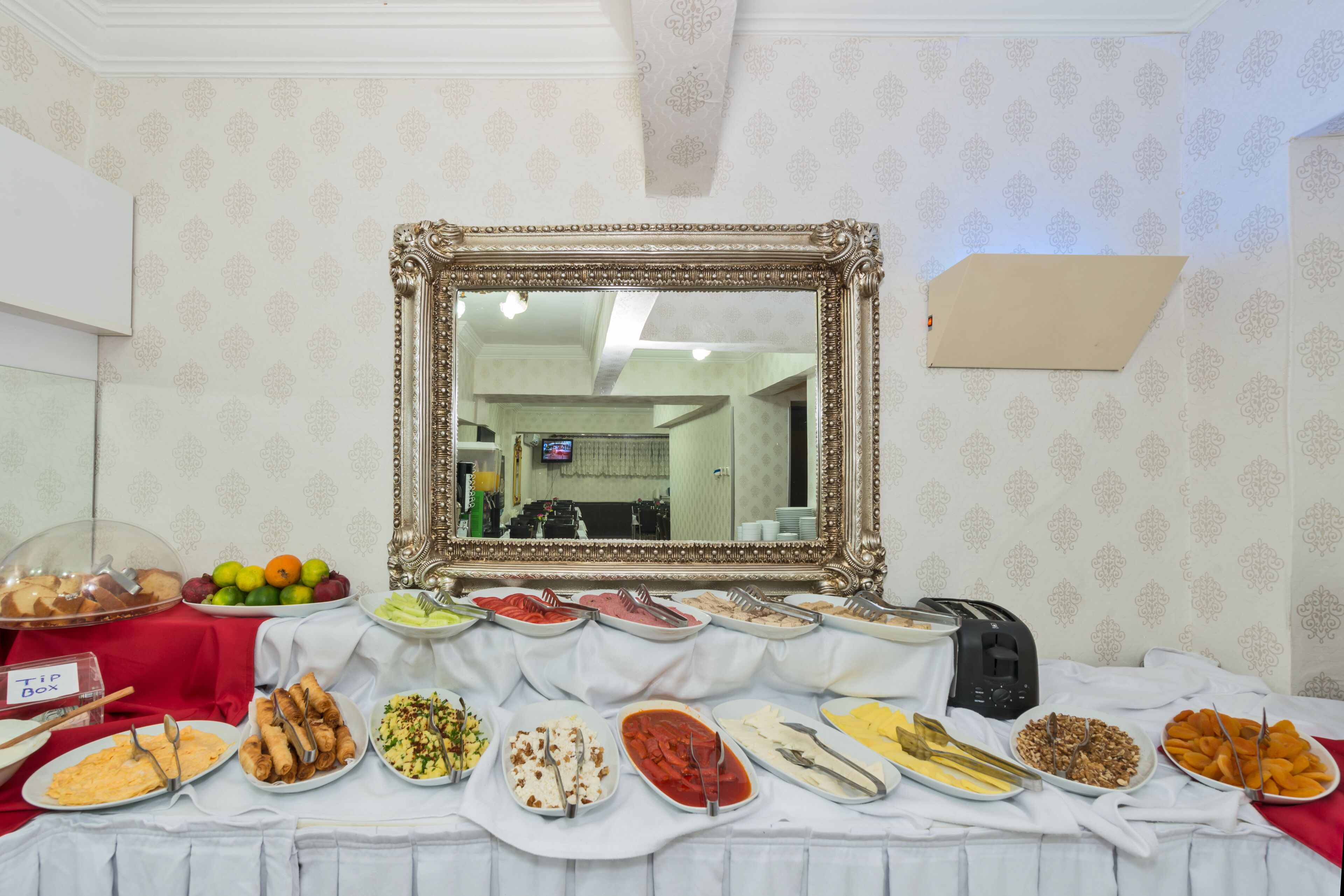 A buffet table with various food items and a mirror above it.