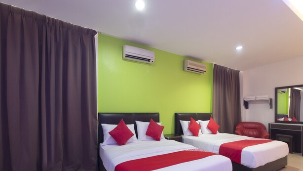 Une chambre d’hôtel avec deux lits, des murs verts et un appareil de climatisation.