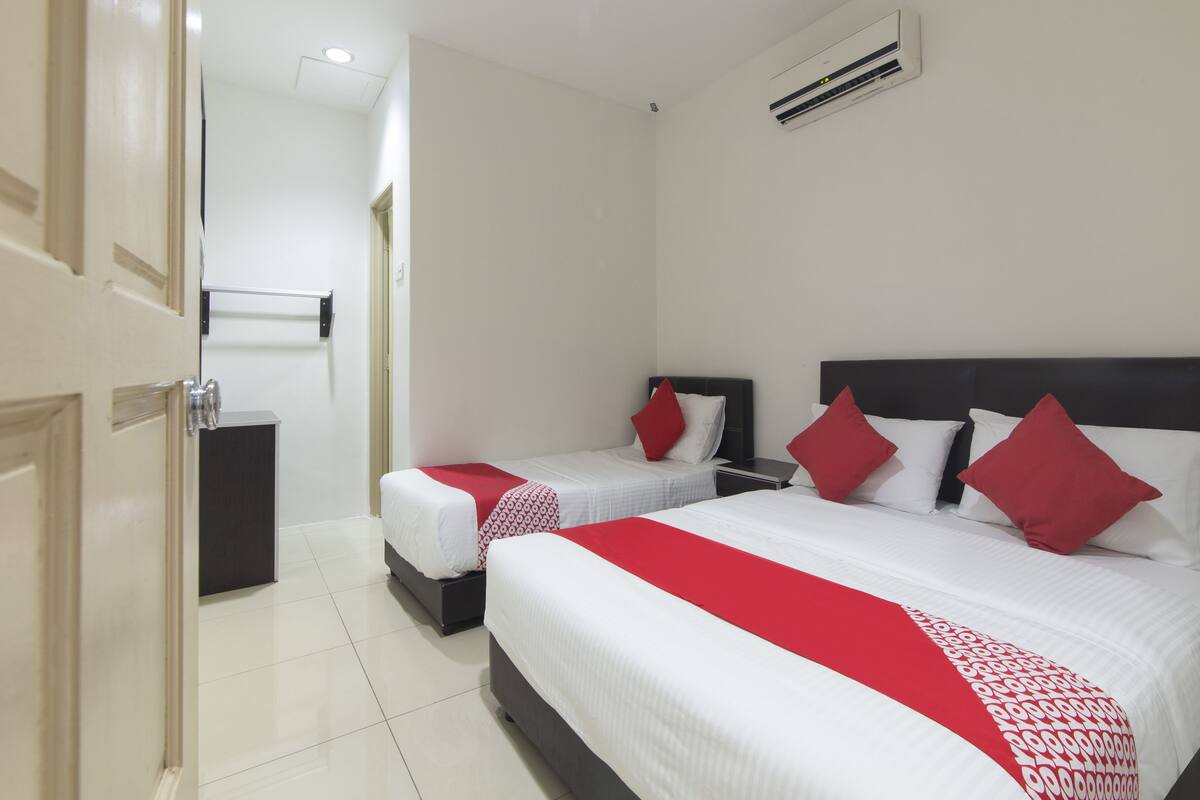 Habitación de hotel con dos camas, una mesita de noche, un armario y un equipo de aire acondicionado.