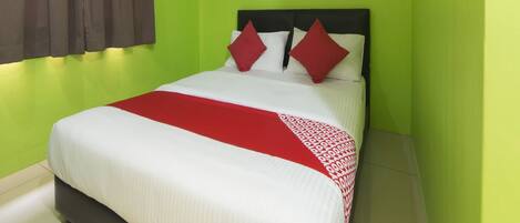 Una habitación de hotel con cama, ventana con cortinas y pared verde.