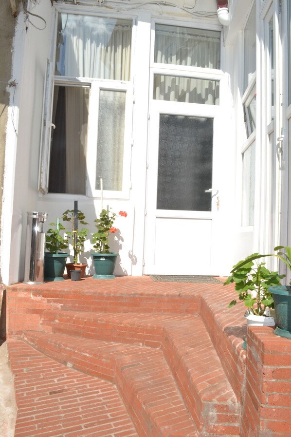 A white door with a window above it, a brick staircase leading up to the door, and potted plants on the steps.