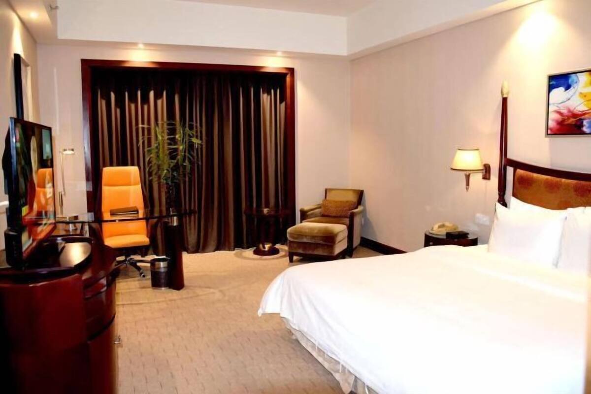 Une chambre d’hôtel équipée d’un lit, d’un bureau, d’une chaise, d’une lampe et d’un téléviseur.