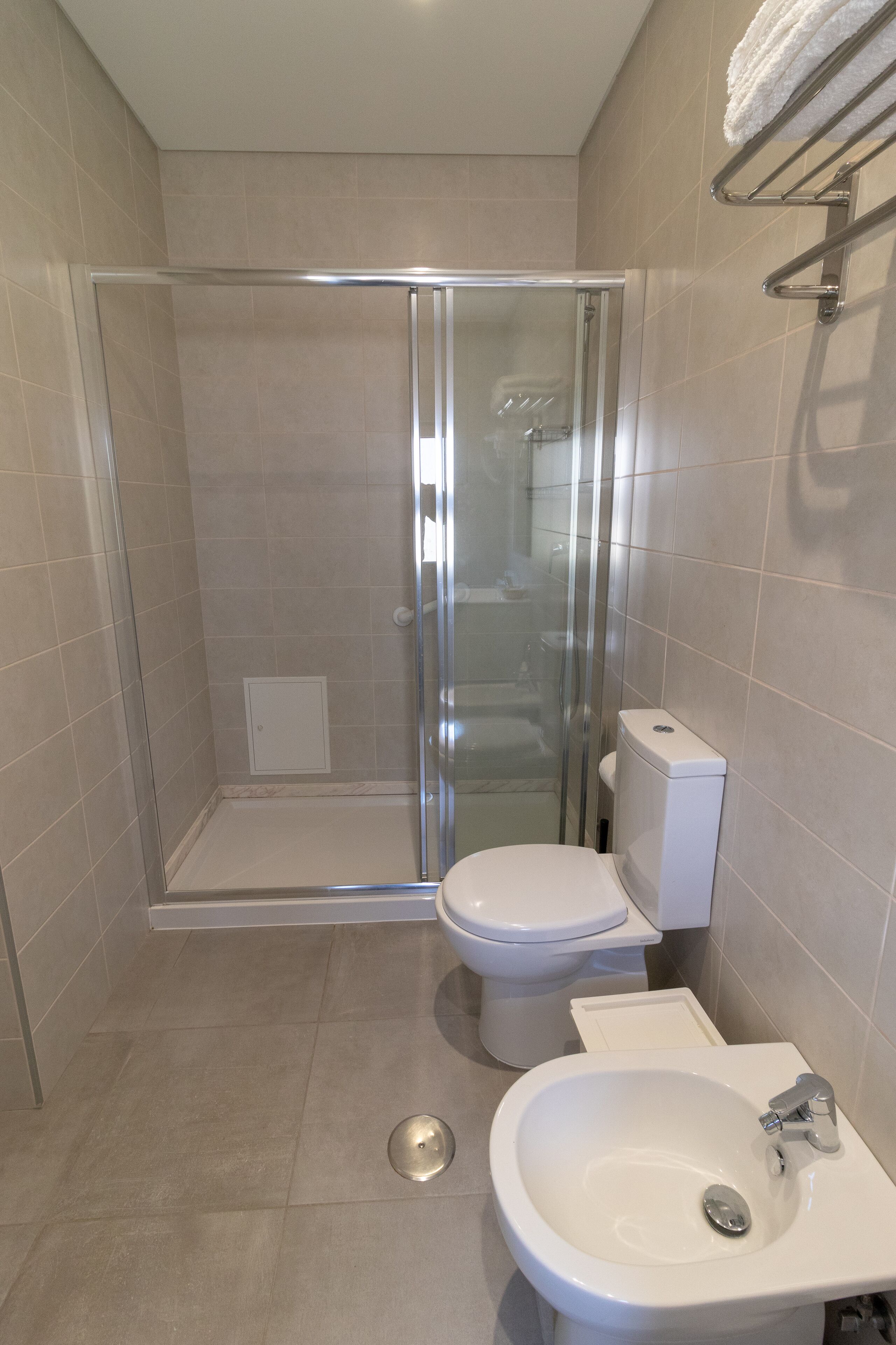 Een moderne badkamer met een douchecabine van glas, een wit toilet en een wastafel met spiegel.