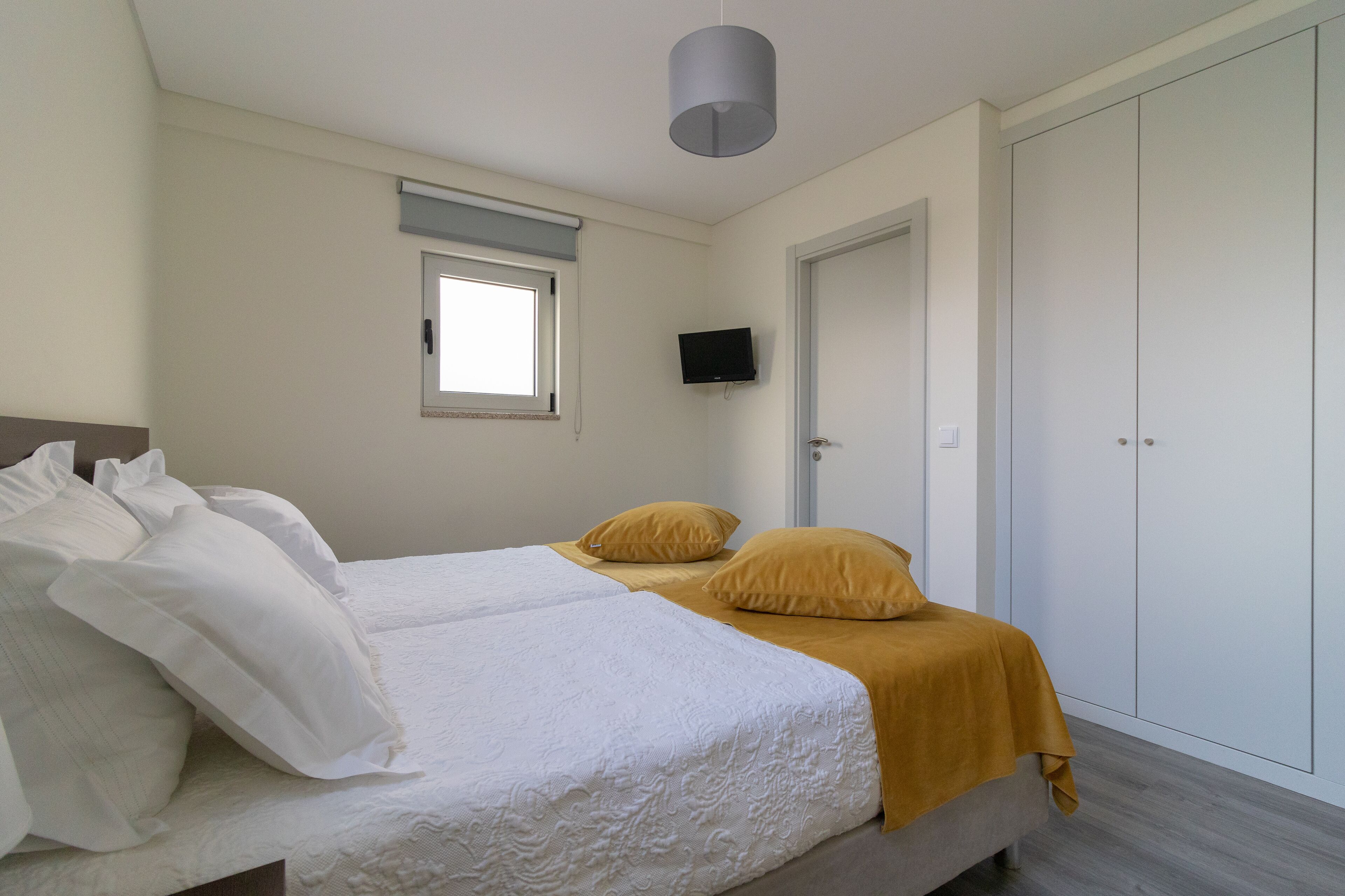 Un dormitorio con cama, televisión, armario y ventana.