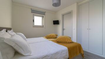 Un dormitorio con cama, televisión, armario y ventana.