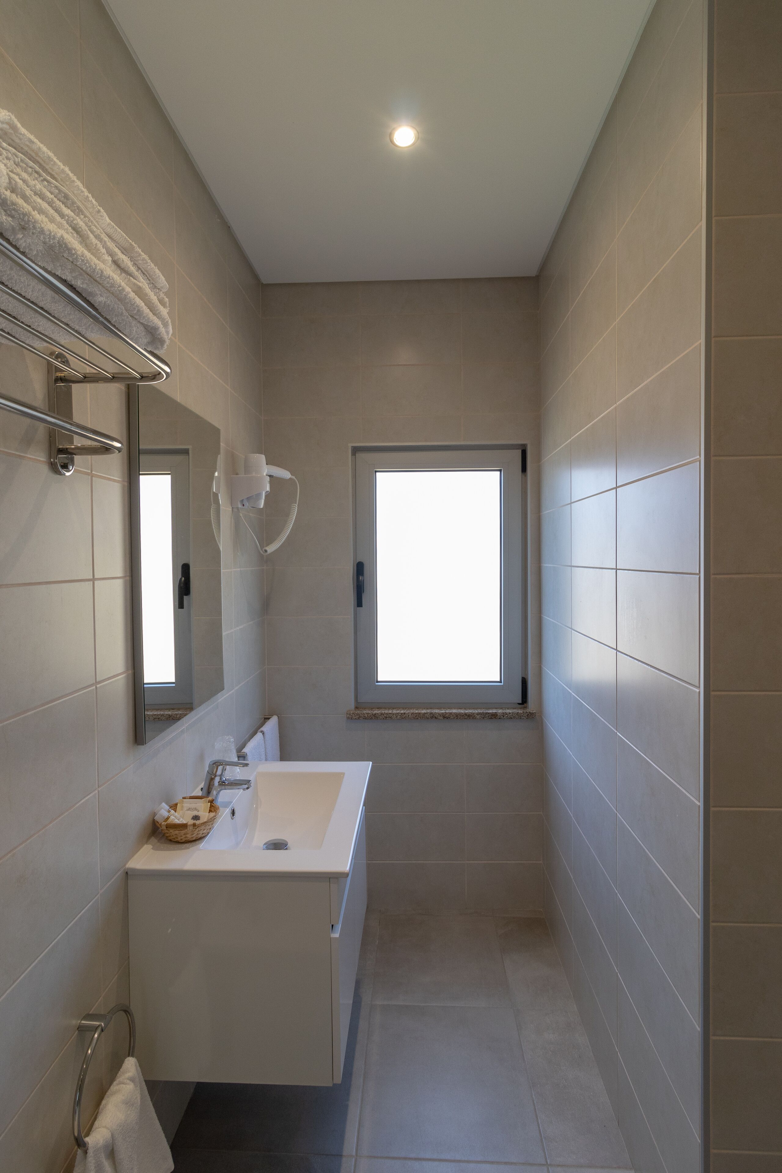 Een moderne badkamer met een grote spiegel, een wastafel en een raam.