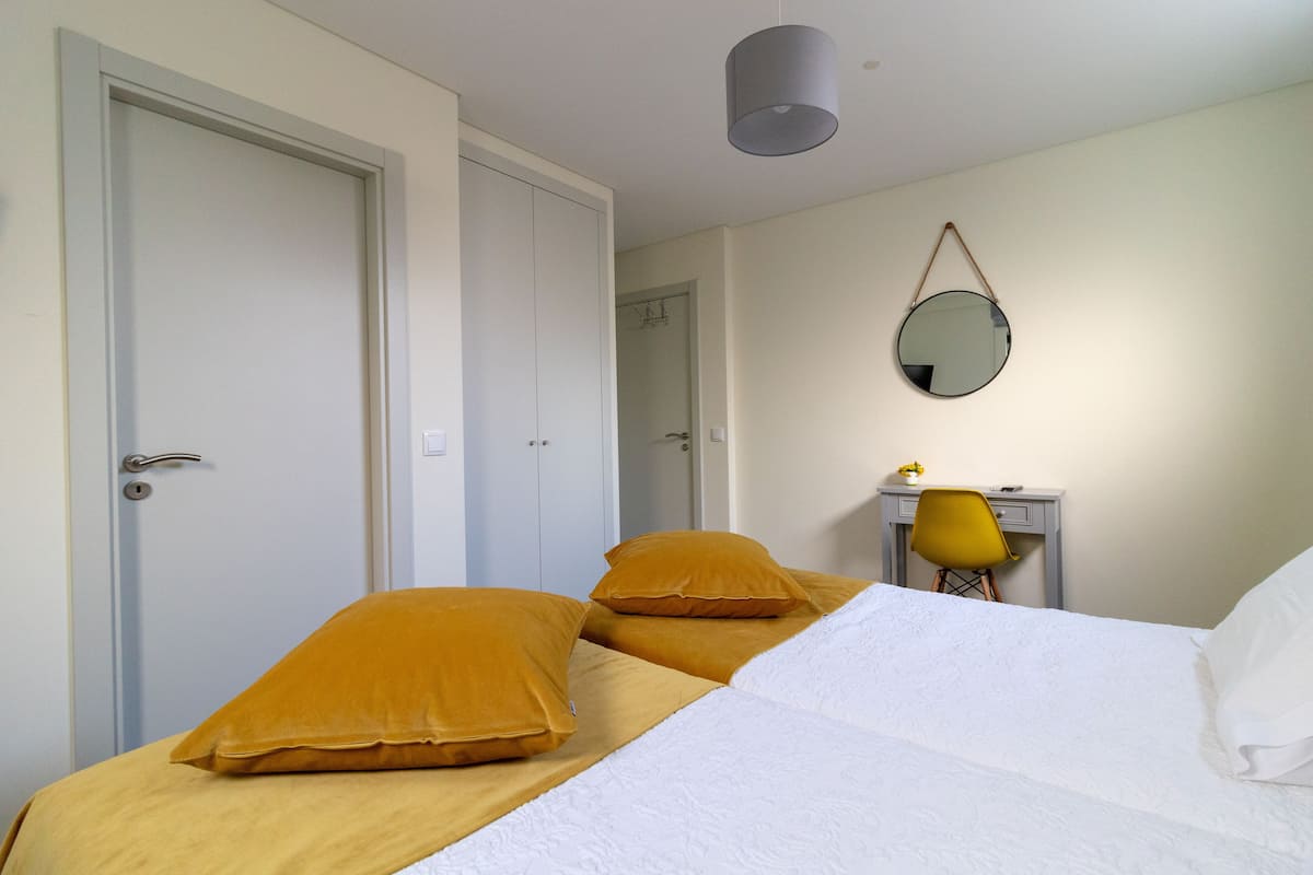 A hotel room with a bed, a desk, a chair, and a mirror.