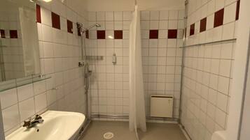 A small, compact bathroom with a white sink, toilet, and shower area.