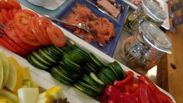 Una mesa de buffet con diversos alimentos, entre ellos frutas cortadas, verduras y carnes.