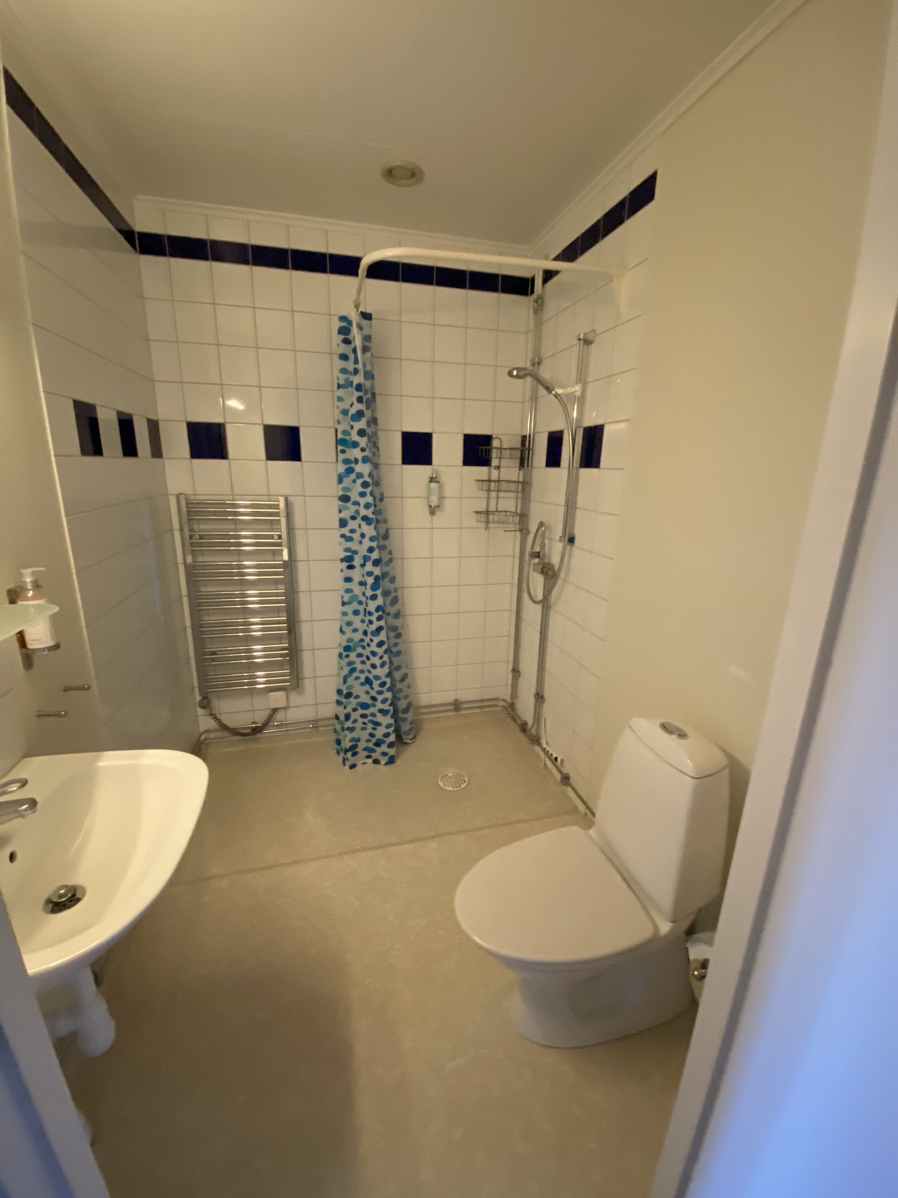 A bathroom with a white sink, toilet, shower, and a towel rack.