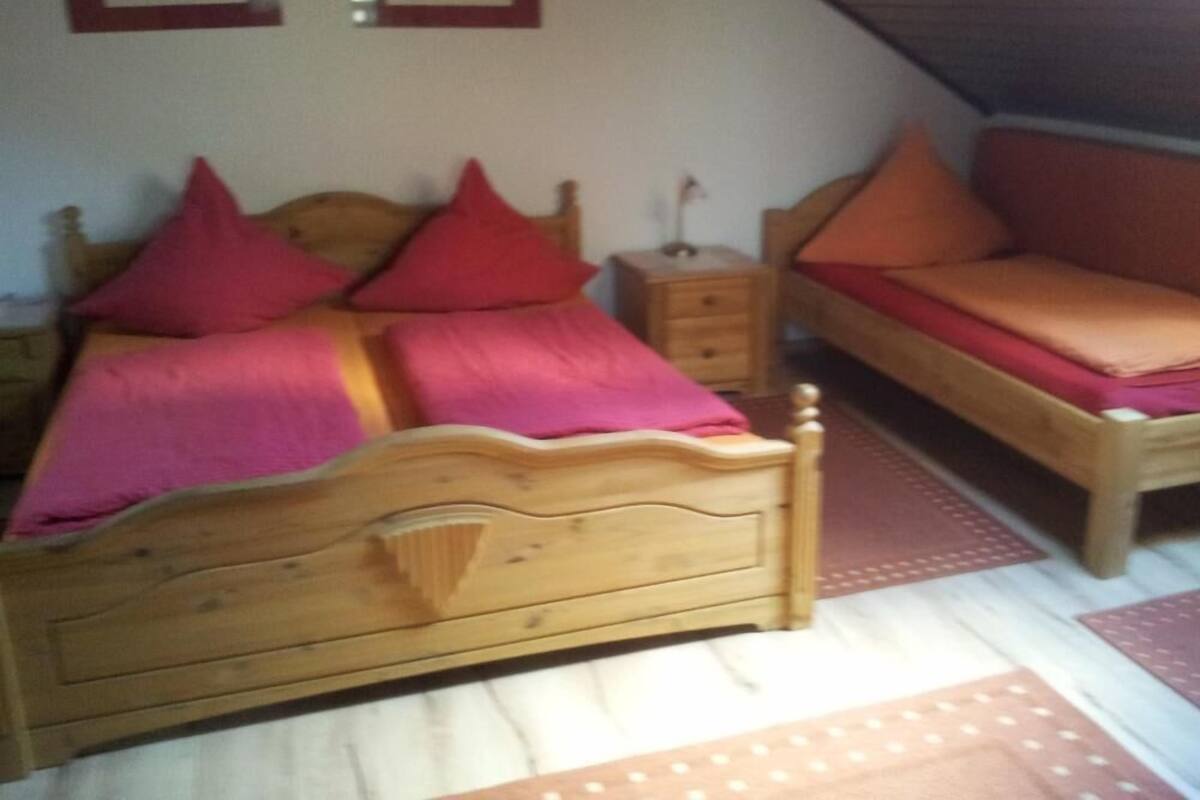 A bedroom with a wooden bed, a wooden nightstand, and a wooden sofa.