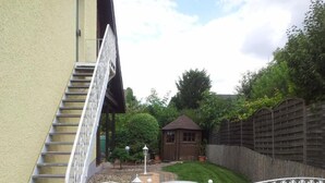 A residential property with a staircase leading to a wooden door, a fenced backyard, and a small wooden structure. - Gästehaus Walter (Offenbach an der Queich)