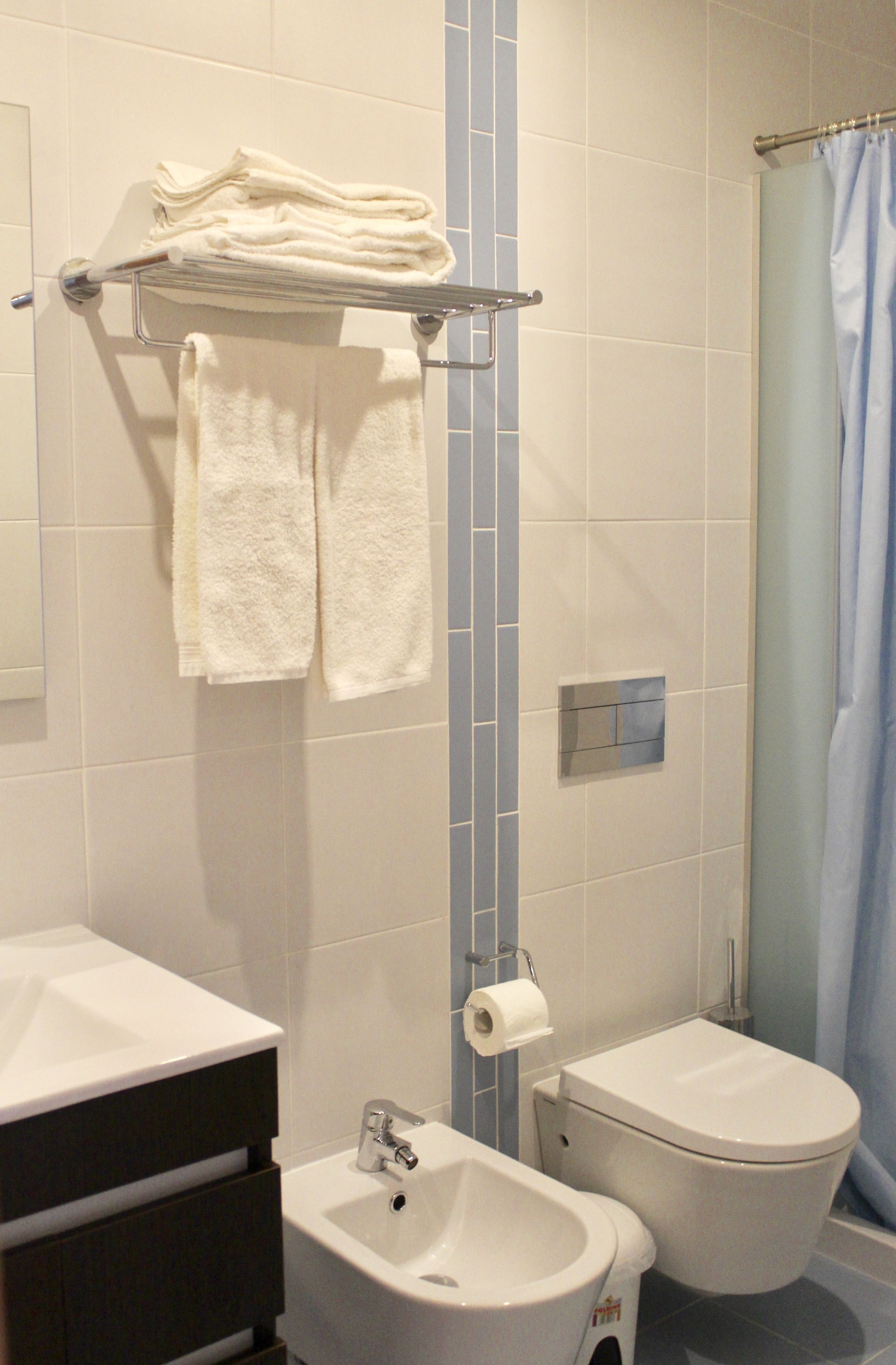 A bathroom with a sink, toilet, and a towel rack with folded towels.