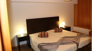 Ein Hotelzimmer mit zwei Betten, einem Holzschrank und Nachttischlampen.