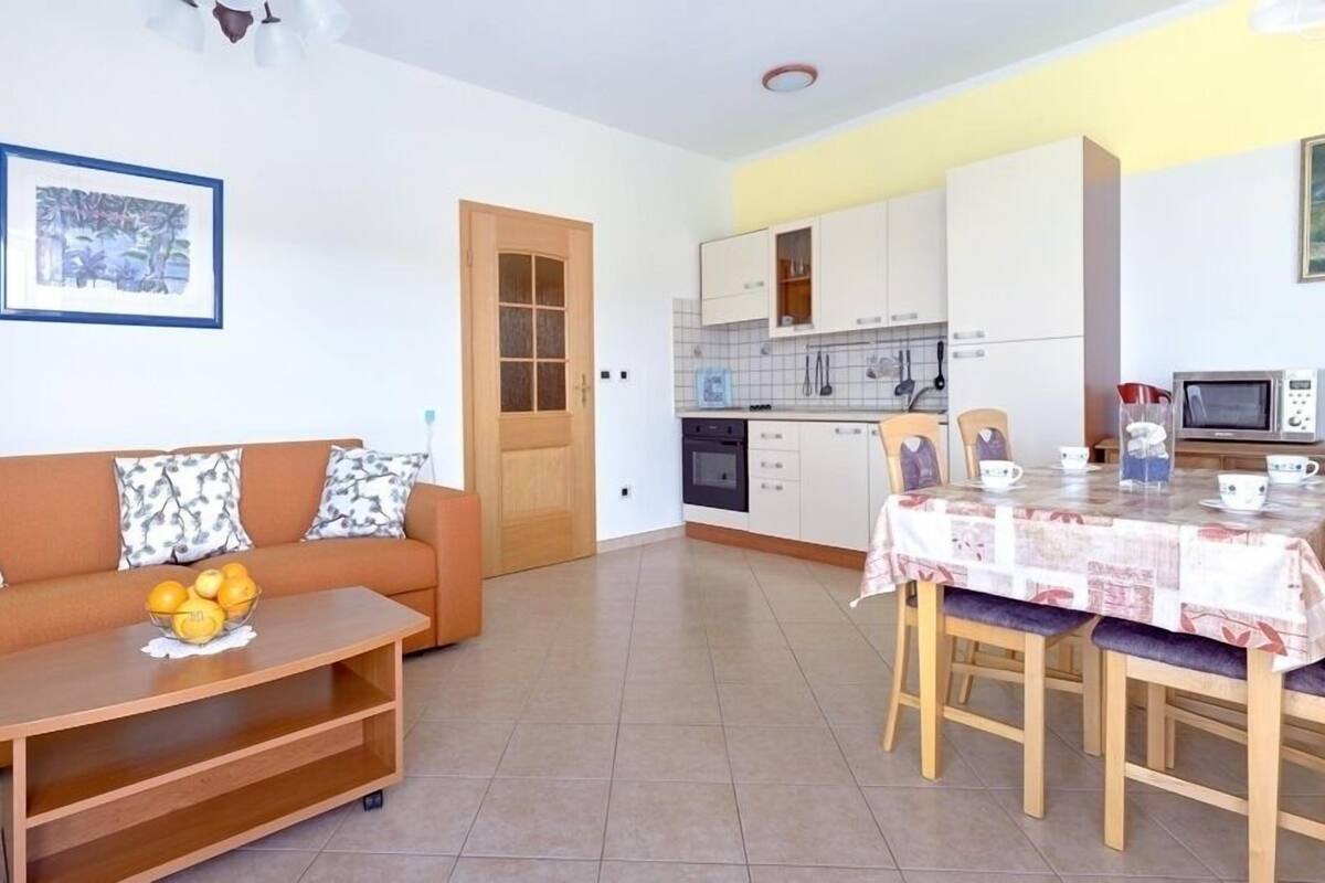 A compact living space with a sofa, a dining table, and a kitchen area.