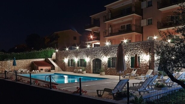 A hotel with a swimming pool, outdoor seating, and a stone wall. - Apartments Villa Venera (Labin)