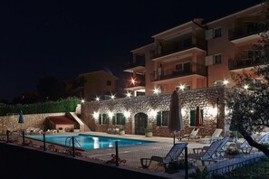 A hotel with a swimming pool, outdoor seating, and a stone wall. - Apartments Villa Venera (Labin)