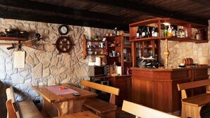 A rustic bar area with wooden furniture, stone walls, and shelves stocked with bottles. - Apartments Villa Venera (Labin)
