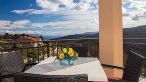 A balcony with a table, chairs, and a vase of yellow flowers. - Apartments Villa Venera (Labin)
