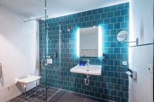 A modern bathroom with a glass shower enclosure, a white sink, and a mirror.