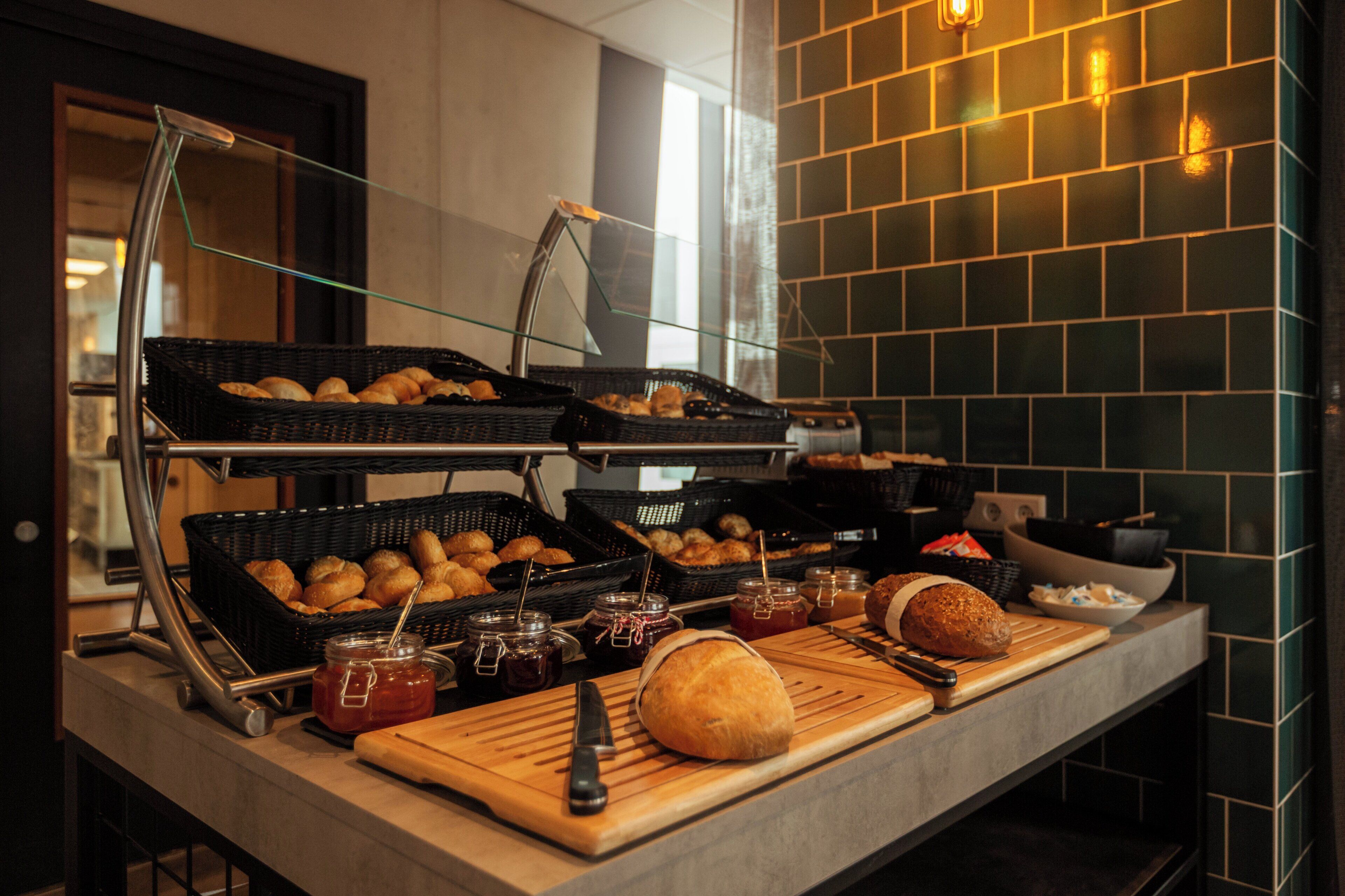 Un buffet proposant une variété de produits de boulangerie, notamment du pain et des viennoiseries, ainsi que des condiments.