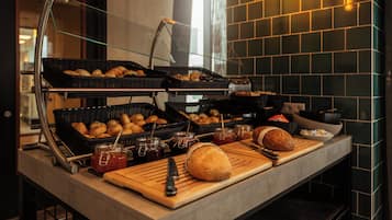 Un buffet proposant une variété de produits de boulangerie, notamment du pain et des viennoiseries, ainsi que des condiments.