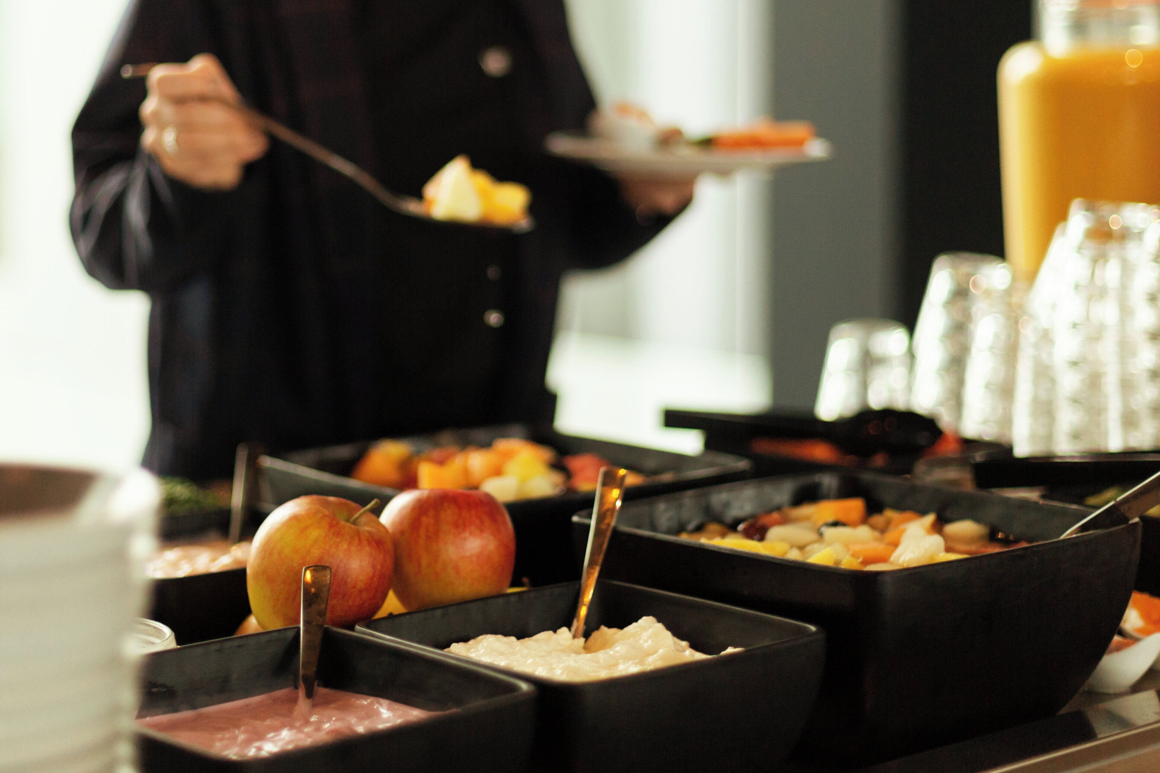 A buffet with various food items and a person serving food.