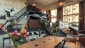 Un interior moderno con una mesa de comedor de madera, sillas, una escalera y una zona de estar con sofás y una mesa de centro.