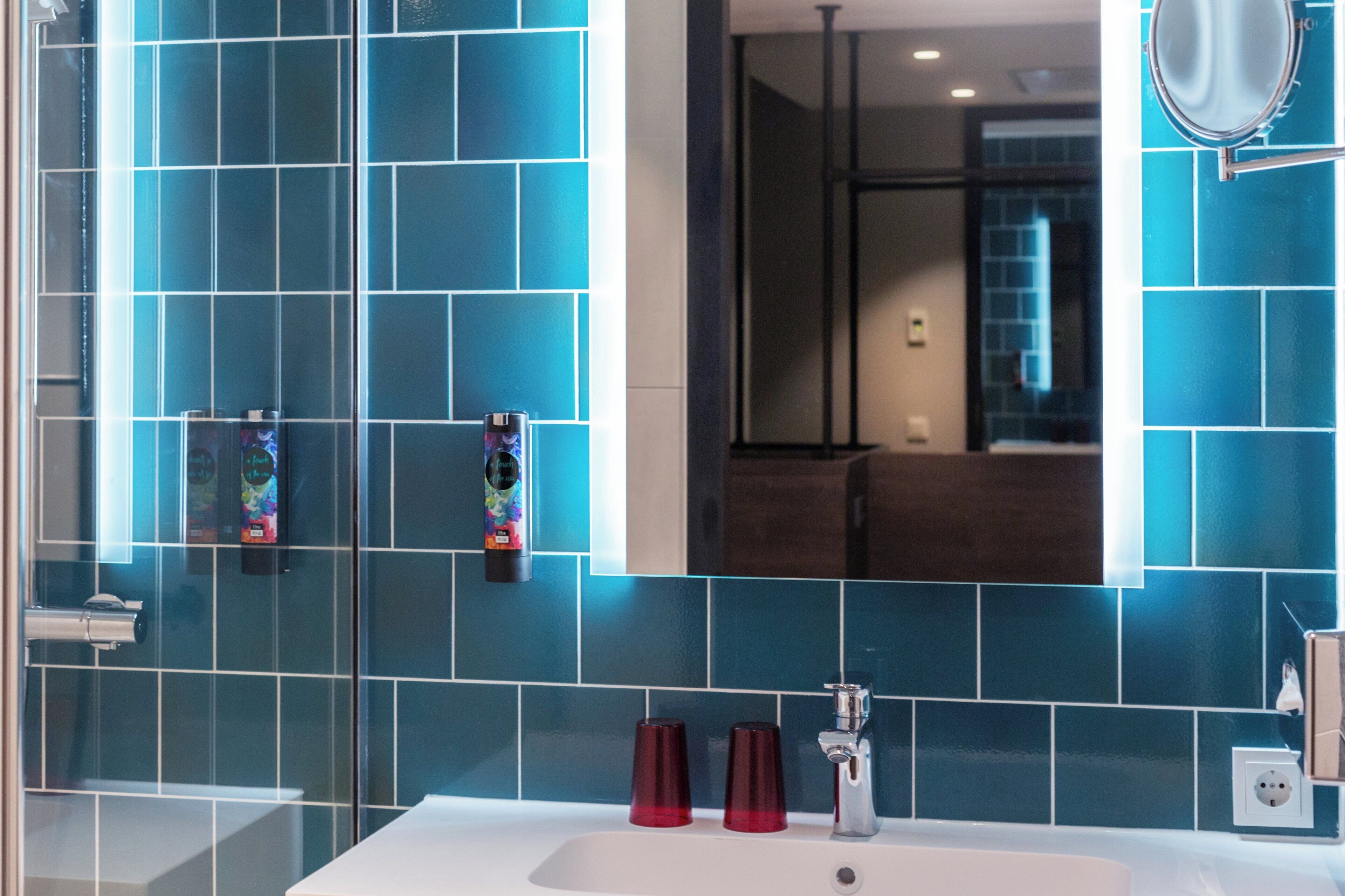A bathroom with blue tiles, a white sink, and a mirror.