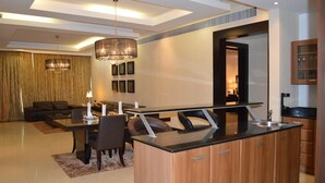 A modern living room with a dining area, a kitchen, and a staircase leading to an upper level.