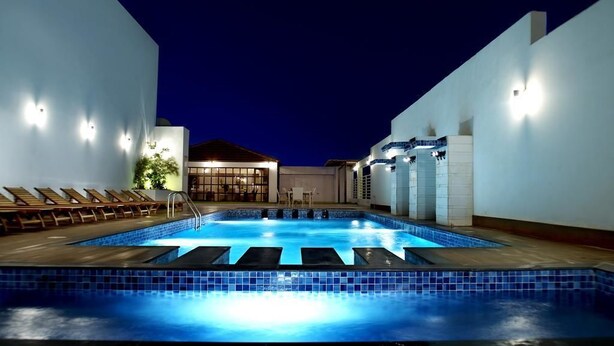 A swimming pool with lounge chairs and a building in the background.